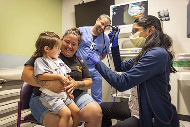 Nurses with child and mom preparing for a laryngoscopy procedure.