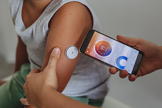 A child's arm with a device that is being read by a smartphone app.