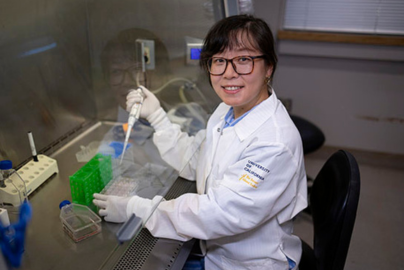 A researcher in a white coat works on experiments in a lab.