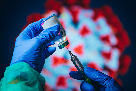 COVID vaccine drawn in front of virus graphic.
