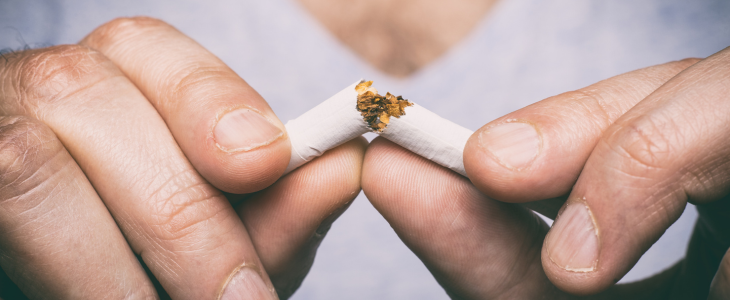Two hands breaking a cigarette in half.