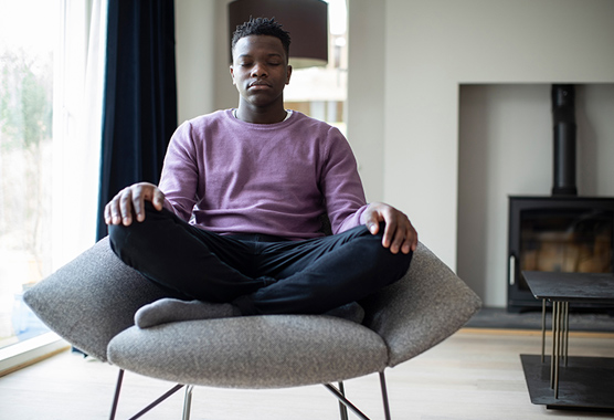 Man sitting on a chair meditating and taking care of his mental health.