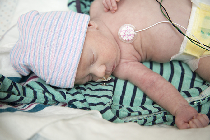 Sleeping baby wearing a beanie with a heart monitor and tube coming from his nose