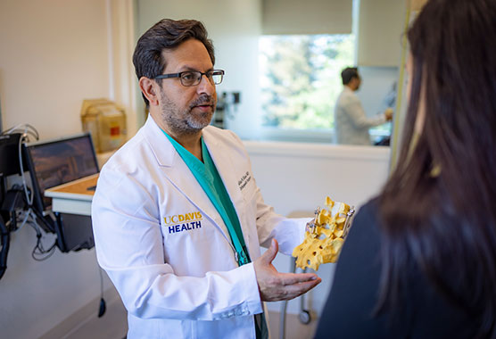 Orthopeadic surgeon showing patient skeletal model for posture-related conditions.