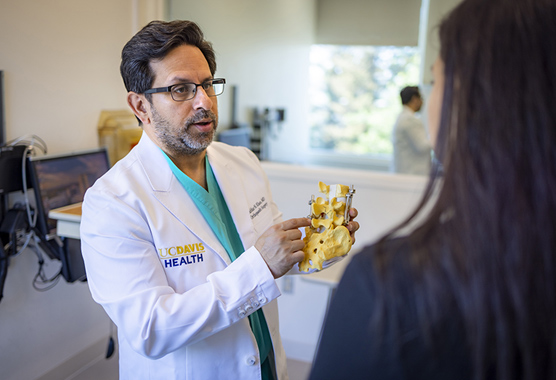 Orthopaedic surgeon showing patient a replica spine while discussing spine conditions.