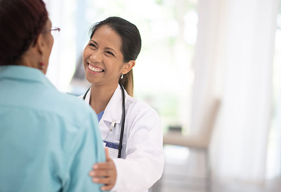 Female health care provider smiling with her hand on a patient's shoulder