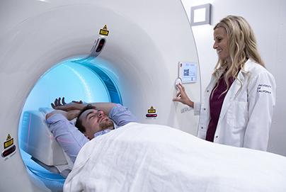 Male patient going into a diagnostic imaging machine and a female provider is smiling at the patient 