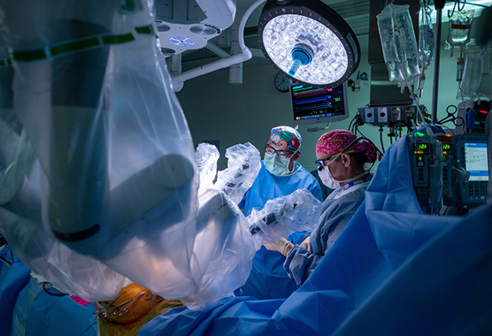 Surgeons implanting pacemaker in patient in operating room.