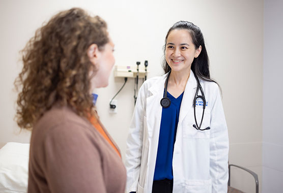 Female provider smiling at a female patient in an exam room.