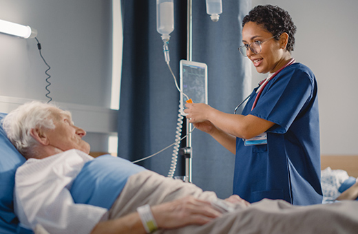 Health care provider talking to patient in hospital bed after thyroid nodule ablation.