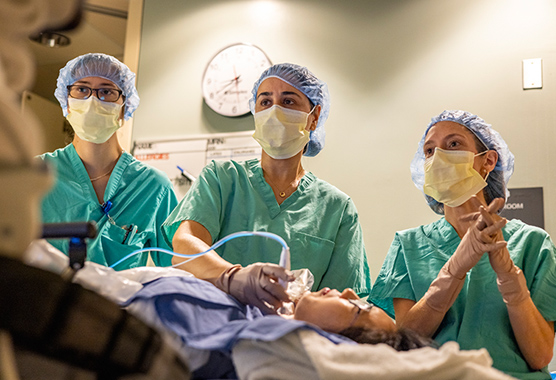 Three health care providers performing thyroid nodule ablation on patient.