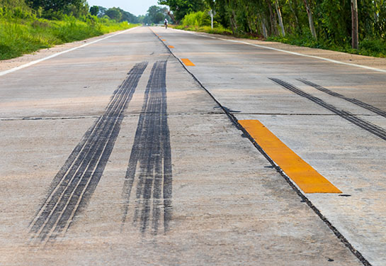 Tire skid marks crossing yellow lines on a road