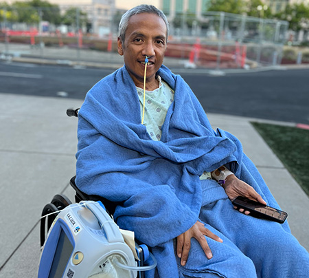 MSgt Salinas on his discharge day in a wheelchair, wrapped in blue blanket.