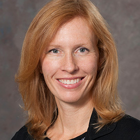 redheaded woman smiling, wearing a white coat