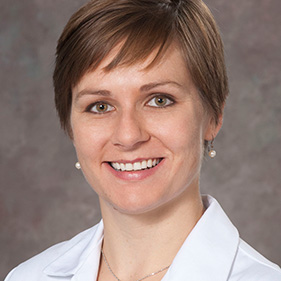 Woman with short light brown hair and wearing a lab coat