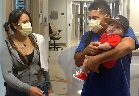 Mom is on the left dad holding baby on the right leaving the hospital floor