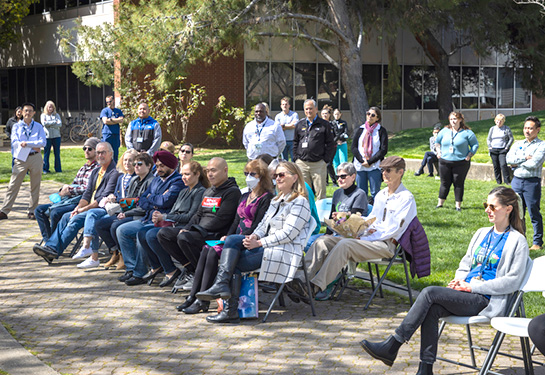 People sitting in chairs and standing looking at someone speak