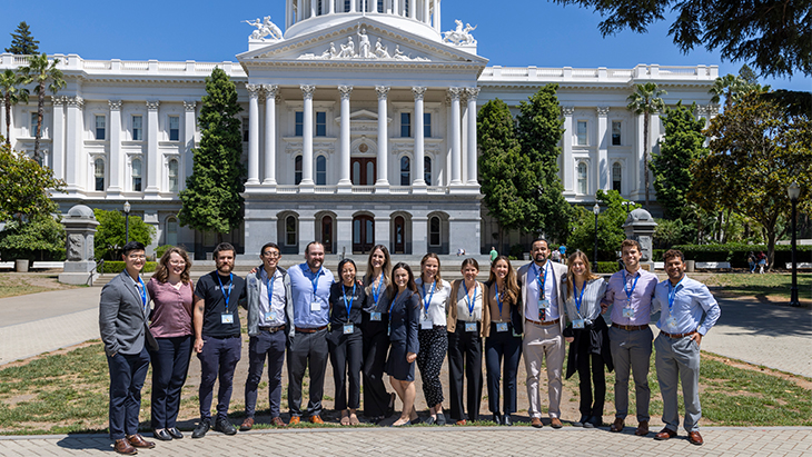 Fifteen students from various medical schools stand in front of the California Capitol before touring the building