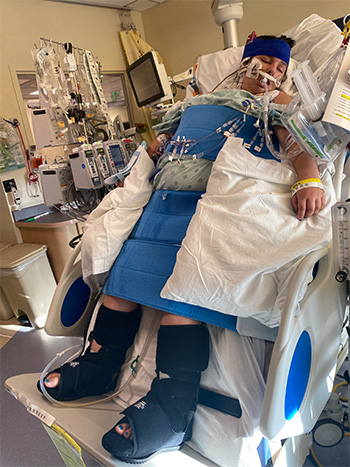 Girl lays on tilt bed upright in hospital. 