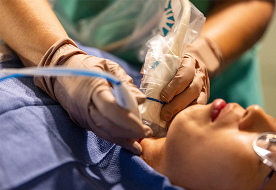 Paciente acostada boca arriba mientras que especialista sostiene un aparato en cada mano  para realizarle un ultrasonido en el cuello 