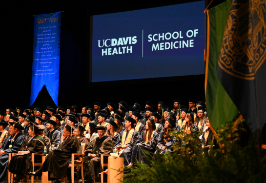 Students in graduation outfit sitting on stage