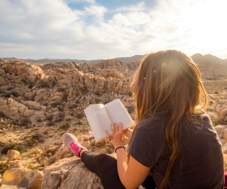 Woman sitting in the canyon, reading a book as the sun rises
