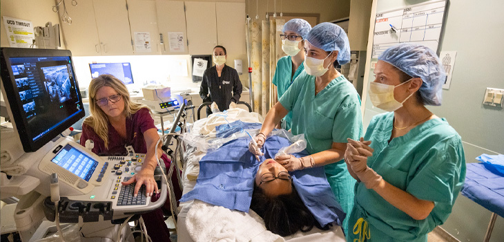 Medical team performs ultrasound-guided thyroid ablation on a patient in a hospital room with monitoring equipment.