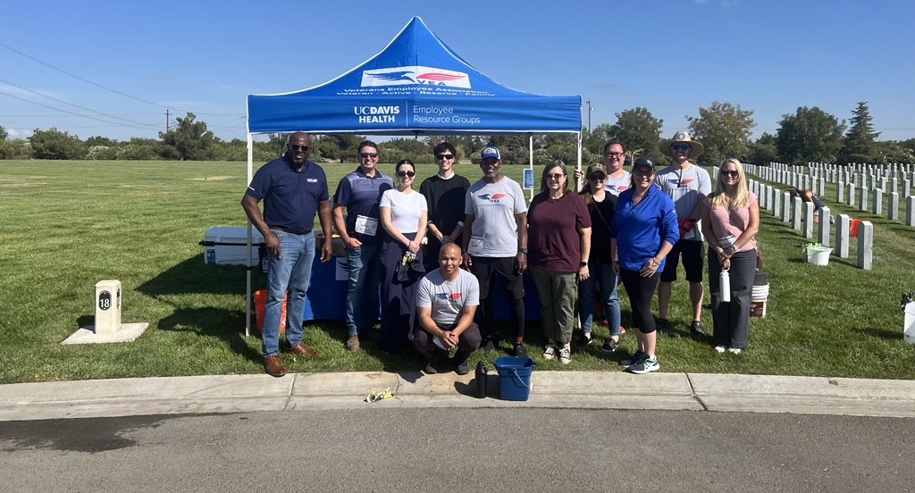 Volunteers stand in front of booth at cemetery 