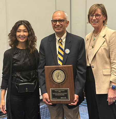 Man holding plaque stands between two women