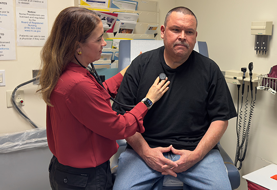 A doctor listens to her patient&#x2019;s heartbeat with a stethoscope during a checkup in a medical exam room.