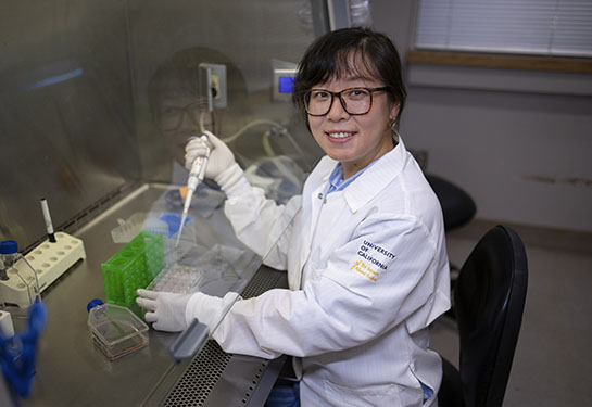 A researcher in a white coat works on experiments in a lab. 