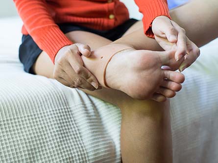 person rubbing the arch of their foot