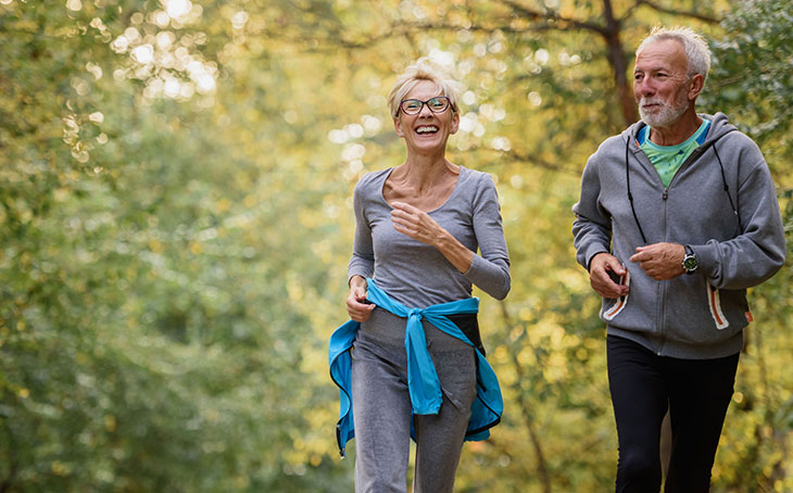 older man and woman walking in a park