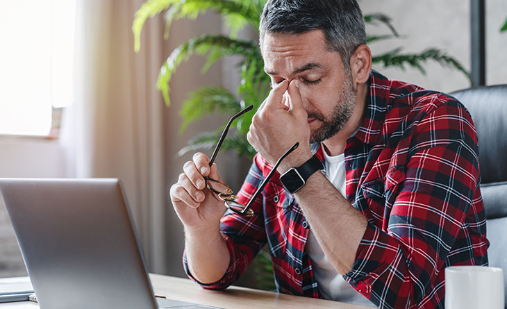 man with a migraine touching is face