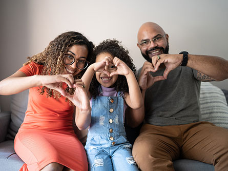 family making heart shapes with their hands