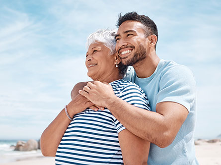 man and his mom on a beach hugging