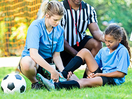 soccer player holding her ankle on the ground