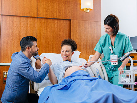 pregnant mother in hospital bed next to father and nurse