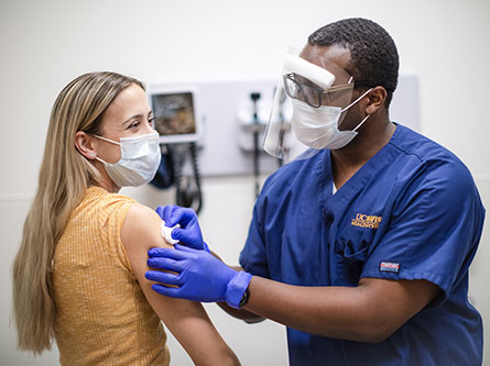 Nurse giving woman a covid and flu shot for symptoms
