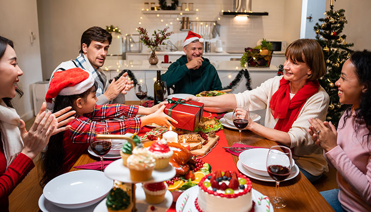 smiling family and friends sitting at a table and smiling for Christmas dinner