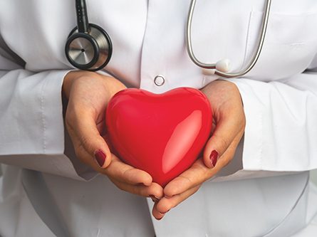 health professional holding a plastic heart shape in her hands with stethoscope around her neck