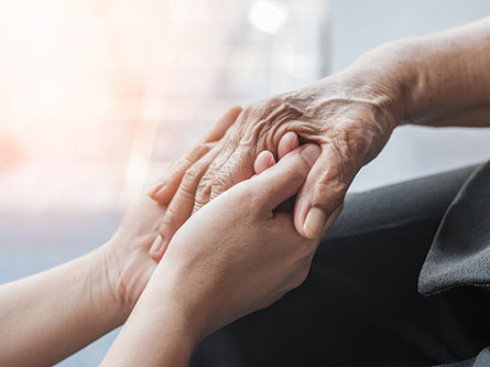 Person's hand holding an older person's hand