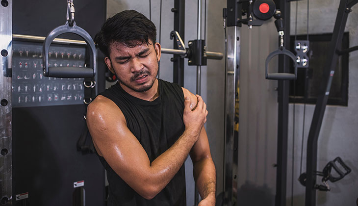 man holding his shoulder with possible torn rotator cuff