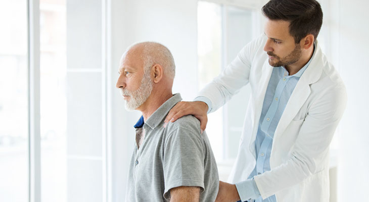 Doctor examining the back of an older adult patient.