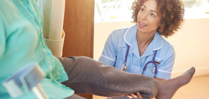 Woman in uniform holds knee of patient.