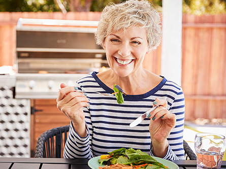 Older woman sitting down to eat, smiling