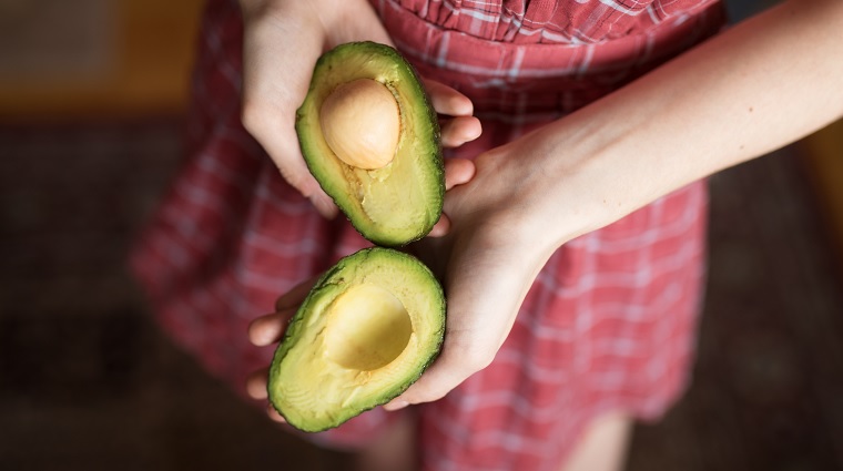 woman holding avocados