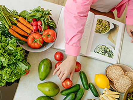 Vegetables on a table with woman ready to cook
