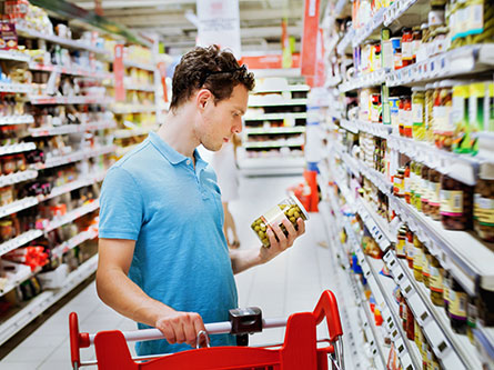 man reading a label on a jar of vegetables
