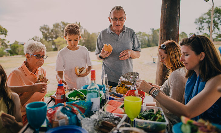 family eating around a table at a park